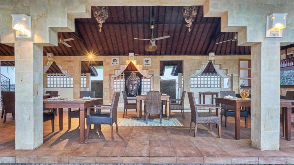 a dining room with wooden tables and chairs at Anda Amed Villas & Spa in Amed