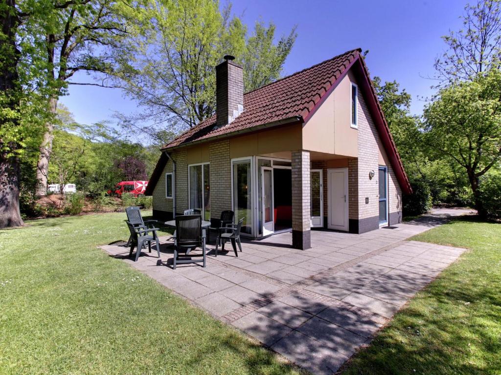 une maison avec une terrasse et des chaises dans la cour dans l'établissement Cozy holiday home with a garden near Zwolle, à Dalfsen