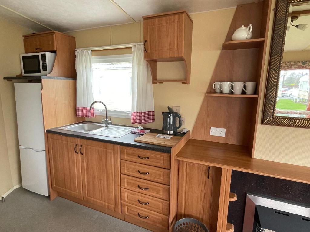 eine kleine Küche mit Holzschränken und einem Waschbecken in der Unterkunft Winchelsea Sands Holiday Park in Winchelsea