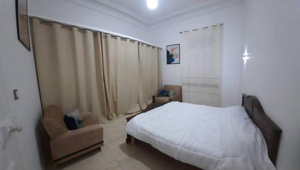 a bedroom with a white bed and a chair at Appartement centre ville in Oran