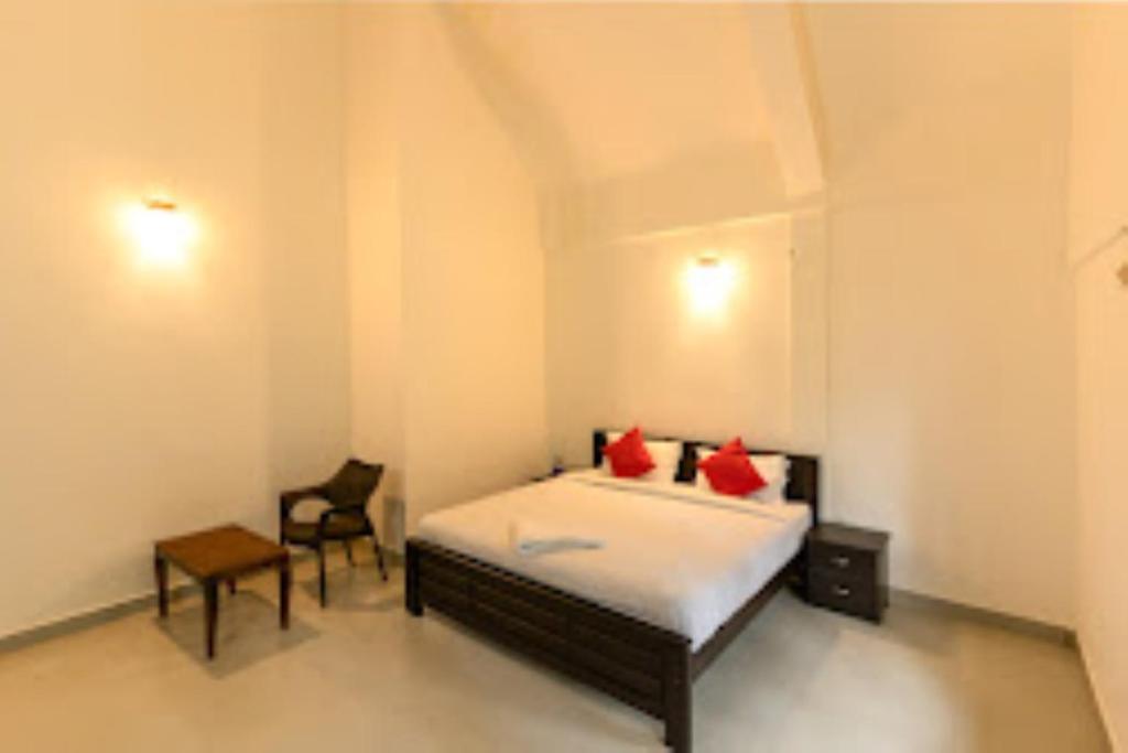 a bedroom with a bed with red pillows and a chair at Cliffotel Kerala in Chithragiri