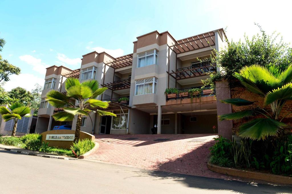 a building with palm trees in front of it at This Twin room is a wandeful selection in Kigali