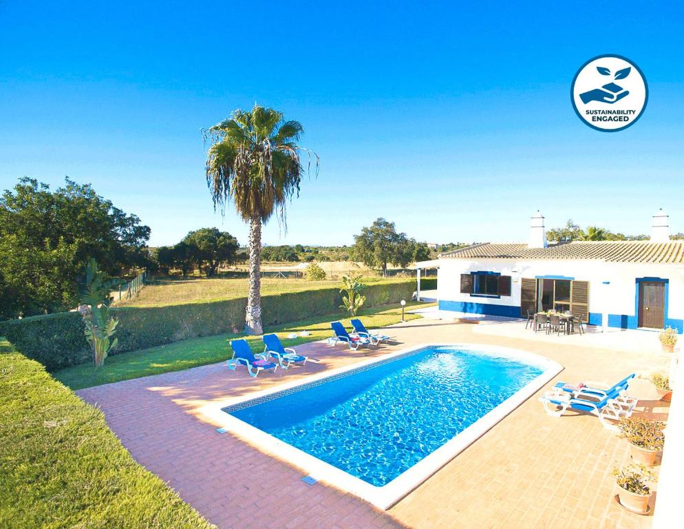 einen Pool mit Stühlen und einer Palme und ein Haus in der Unterkunft Villa Martinica by Algarve Vacation in Guia