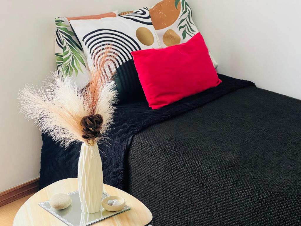 - un lit noir avec un oreiller rouge et un vase sur une table dans l'établissement Luxe et charme Méditerranéen face à la promenade des Anglais, à Nice