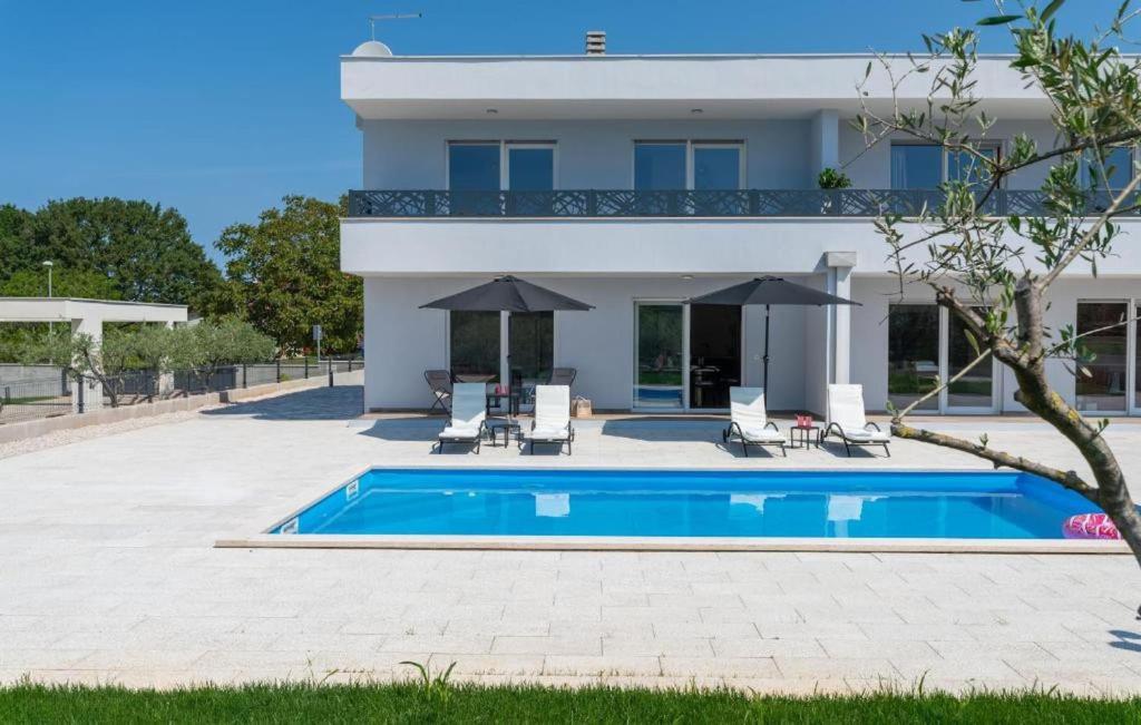 une villa avec une piscine en face d'une maison dans l'établissement Modern villa Casa Storija with pool in Novigrad, à Bužinija