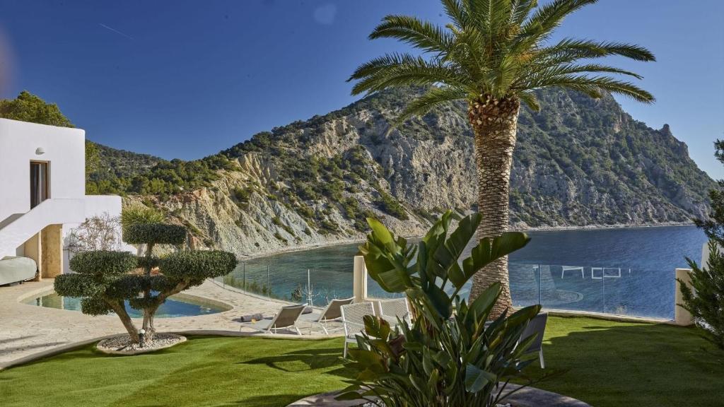 a house with a palm tree and a view of the water at Villa Lunablanca in Santa Eularia des Riu