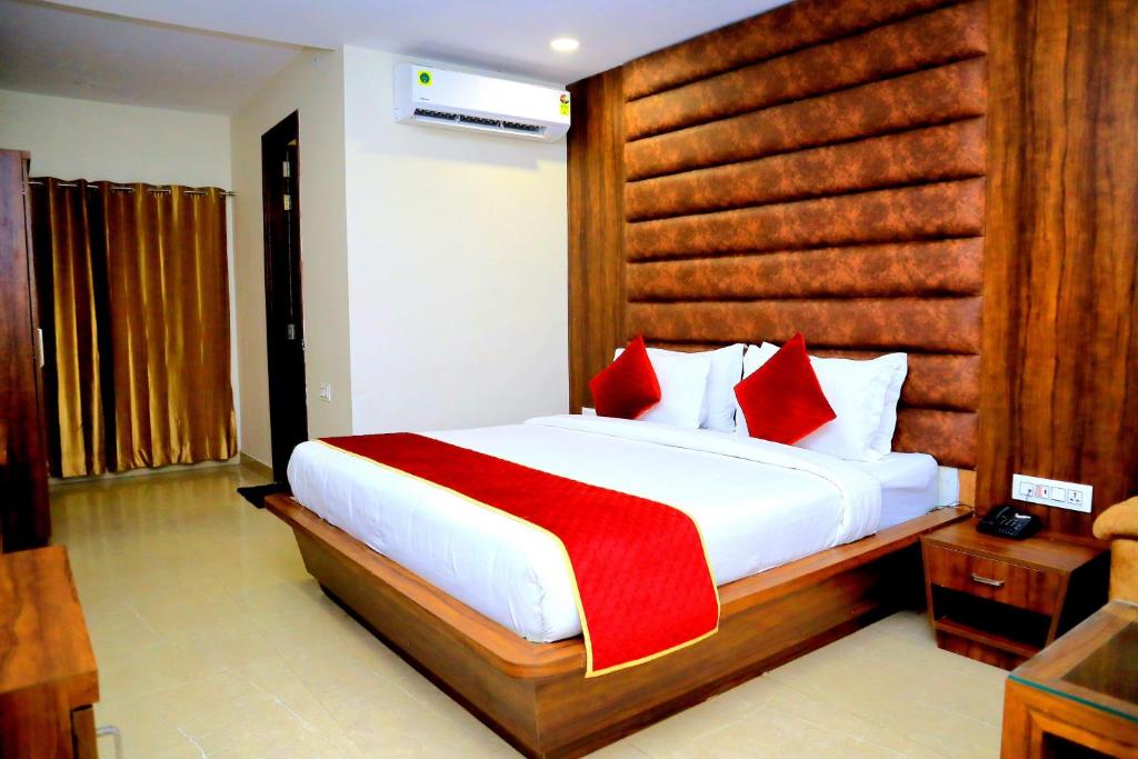 a bedroom with a large white bed with red pillows at Pineberry Hotels in Amritsar