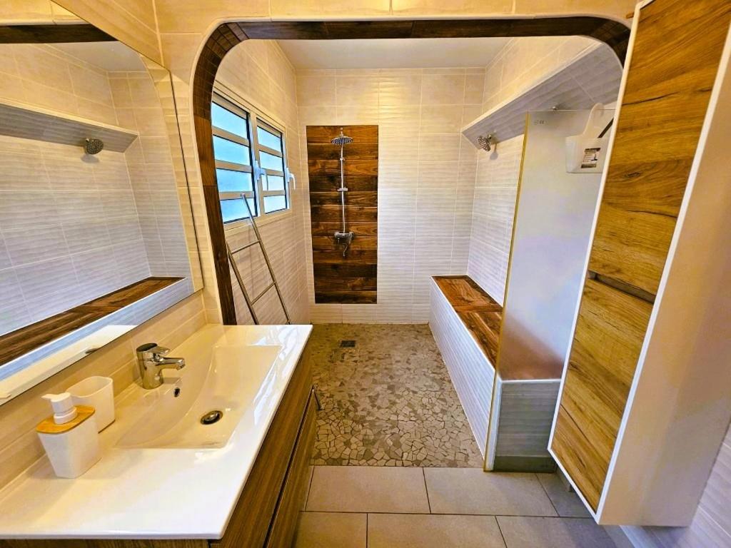 La salle de bains est pourvue d'une baignoire, d'un lavabo et d'une douche. dans l'établissement Charme du Nord 1, à Sainte-Clotilde