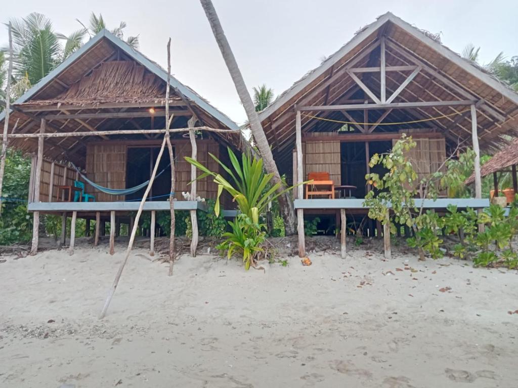 a resort with two huts on the beach at Bruno Raja Ampat Homestay in Pulau Mansuar