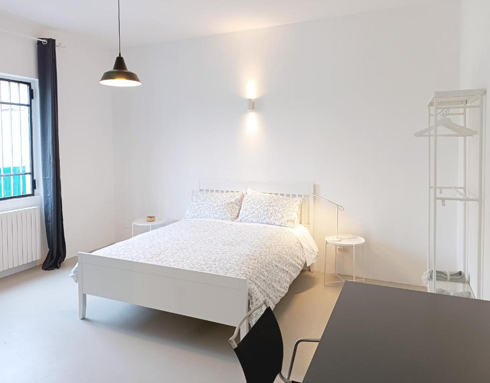 een witte slaapkamer met een wit bed en een tafel bij appartamenti olivo in Vigevano