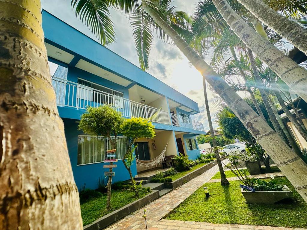 a blue building with palm trees in front of it at Pousada Lagoa Encantada in Garopaba
