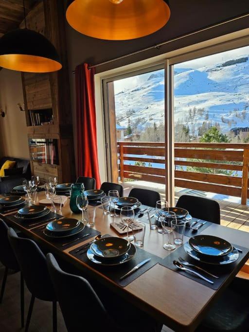 une grande table avec des chaises et une grande fenêtre dans l'établissement L'écrin appartement 4 chambres 4 salles d eau, à Les Deux Alpes