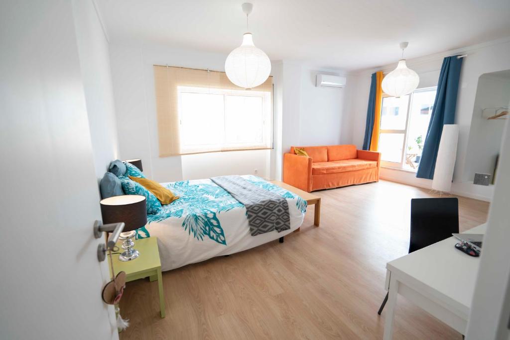 um quarto com uma cama e uma cadeira laranja em Villa Paraíso da Caparica em Charneca de Caparica