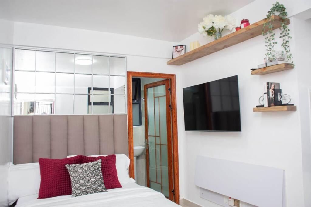 a bedroom with a bed and a tv on a wall at GWETH STUDIO APARTMENT in Nairobi