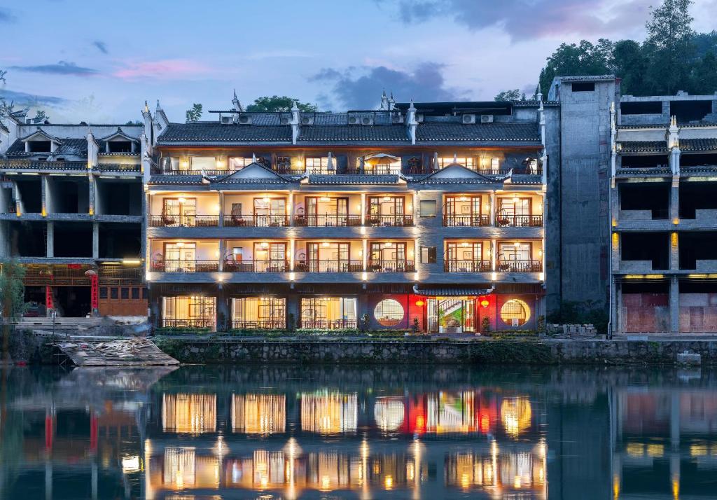 凤凰溪桥夜语江景民宿(凤凰古城沱江店)的水体旁的一座有照明的建筑