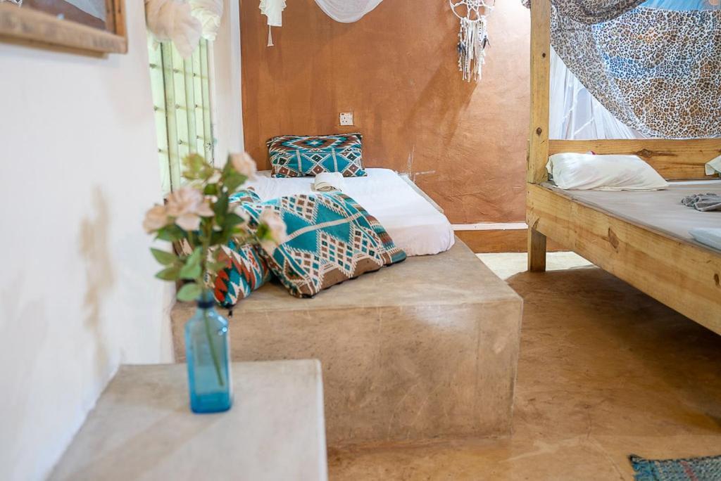 a room with a bed and a vase of flowers on a table at Mawingu lodge in Kizimkazi