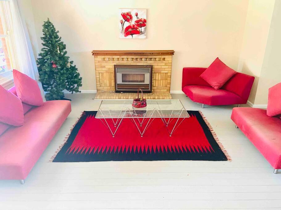 a living room with a red couch and a fireplace at House At the Heart of Shellharbour in Shellharbour