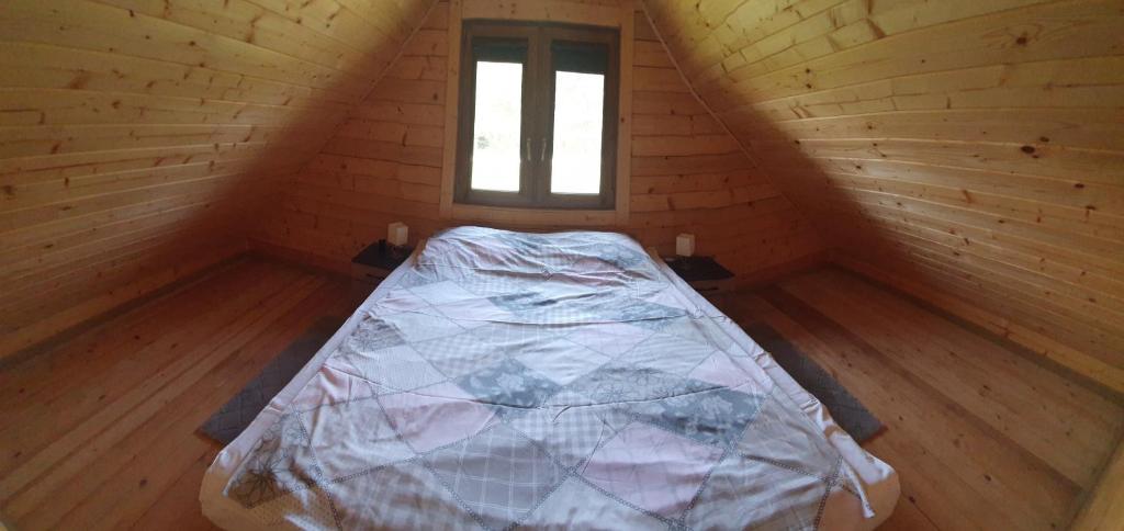 a bed in a wooden room with a window at Domki z bala przy plaży Orle Jezioro Głuszyńskie in Orle