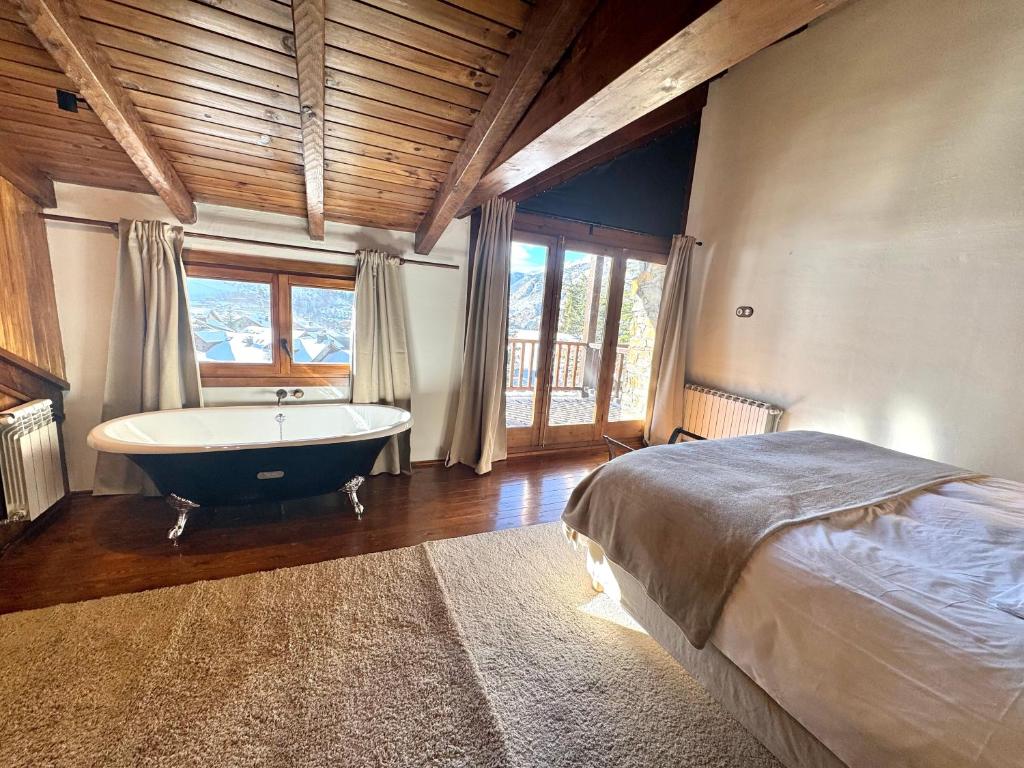 een slaapkamer met een groot bed en een bad bij Apartamento Rustic Chic 28C in El Tarter