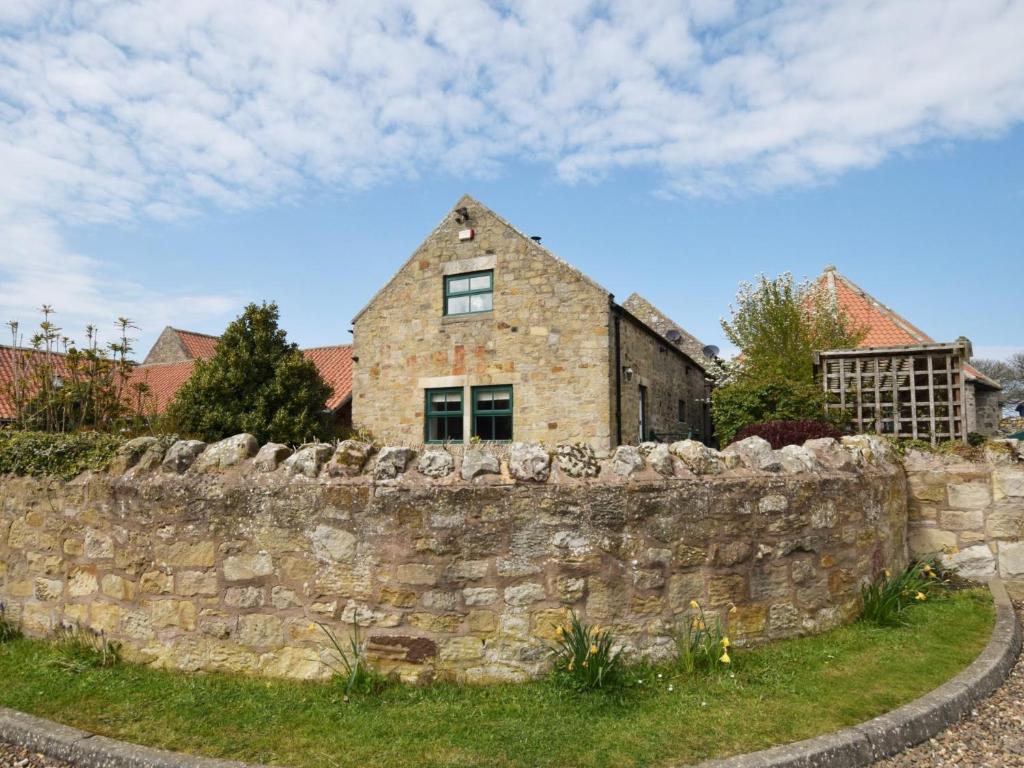 eine alte Steinmauer mit einem Haus dahinter in der Unterkunft 3 bed in Bamburgh 87918 in Bamburgh