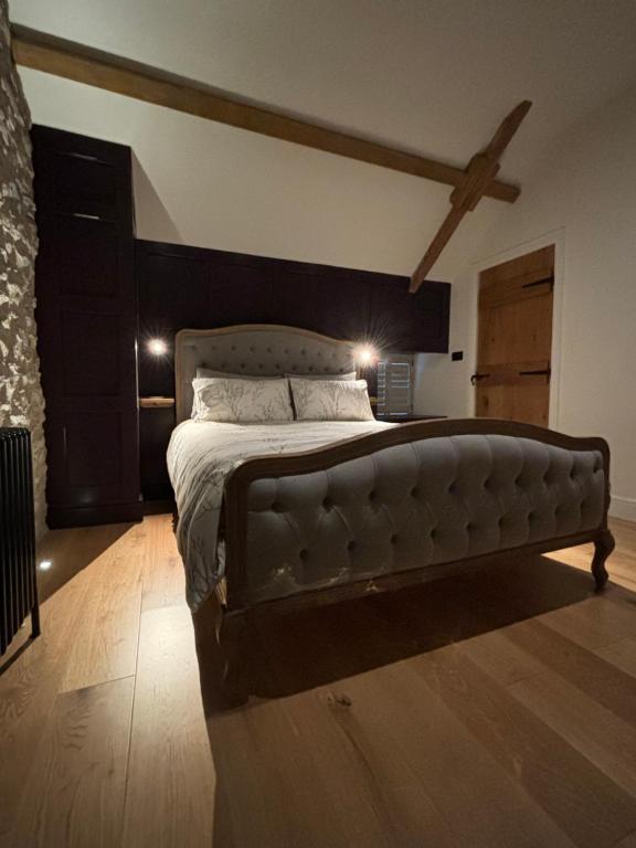 Schlafzimmer mit einem großen Bett mit einem Kopfteil aus Leder in der Unterkunft The Cottage, Everards Farm in Chewton Mendip