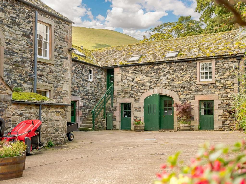 a stone building with green doors and a hill in the background at 1 Bed in Mosedale 88201 in Mosedale