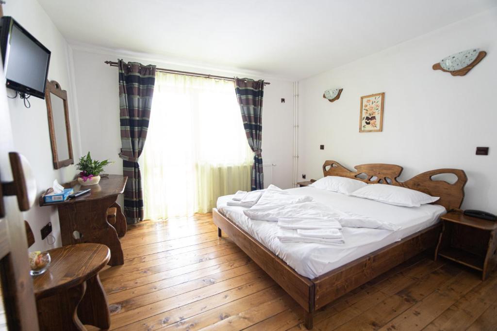 ein Schlafzimmer mit einem Bett und einem großen Fenster in der Unterkunft Pensiunile Zori de Zi si Apus de Soare in Beliş