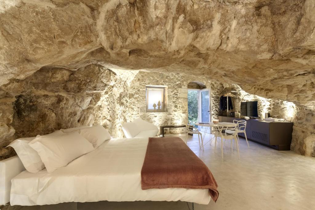 ein Schlafzimmer in einer Höhle mit einem Bett und einem Tisch in der Unterkunft Locanda Don Serafino Historical Boutique Hotel in Ragusa