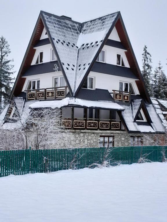 uma casa com um telhado triangular na neve em Stary Bór em Murzasichle
