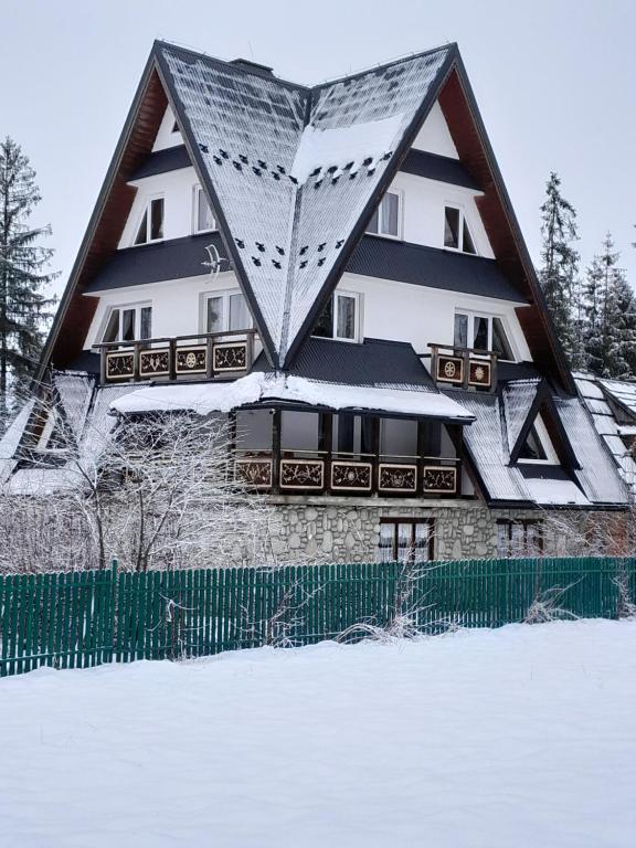 a house with a triangular roof in the snow at Stary Bór in Murzasichle