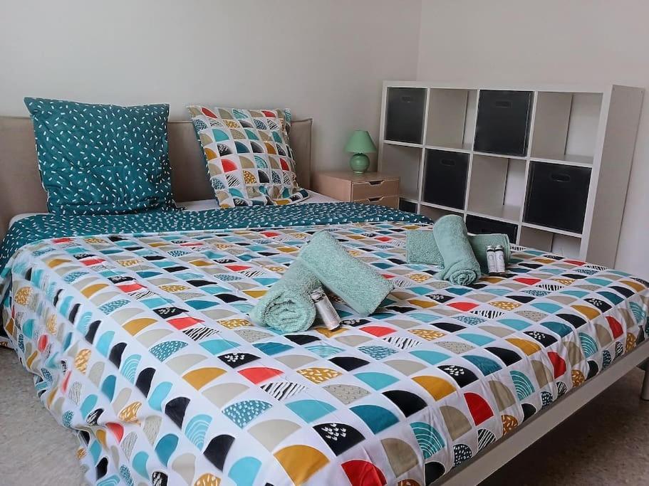 uma cama grande com um edredão colorido e almofadas em 100m des plages centre Antibes em Antibes