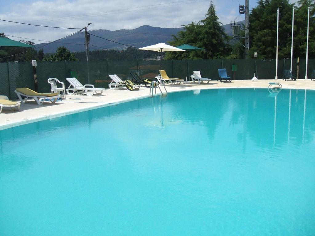 ein großer blauer Pool mit Stühlen und einem Sonnenschirm in der Unterkunft Hotel Boavista I in Melgaço