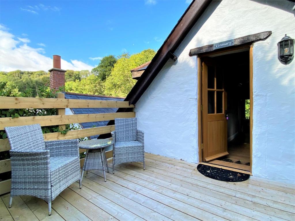 a wooden deck with two chairs and a door at 1 Bed in Exmoor National Park 89766 in Parracombe