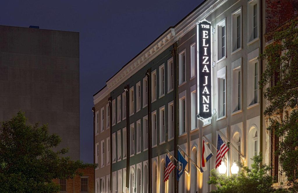een bord aan de zijkant van een gebouw met Amerikaanse vlaggen bij The Eliza Jane, in The Unbound Collection by Hyatt in New Orleans