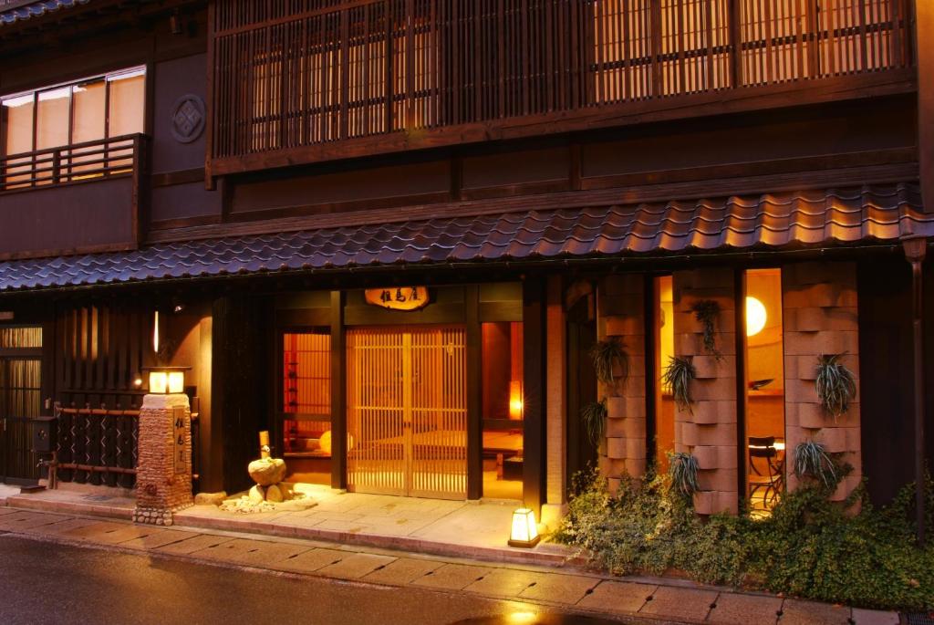 城崎温泉 但馬屋-Tajimaya- في تويوكا: مدخل لمبنى في الليل مع وجود انوار