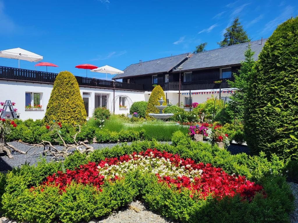 a garden with red and white flowers in front of a building at Dom Wczasowy Lazur in Wicie