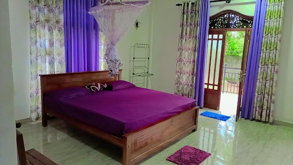 Bett mit violetter Bettwäsche in einem Zimmer mit Fenster in der Unterkunft Sunrise Relax Inn in Beruwala