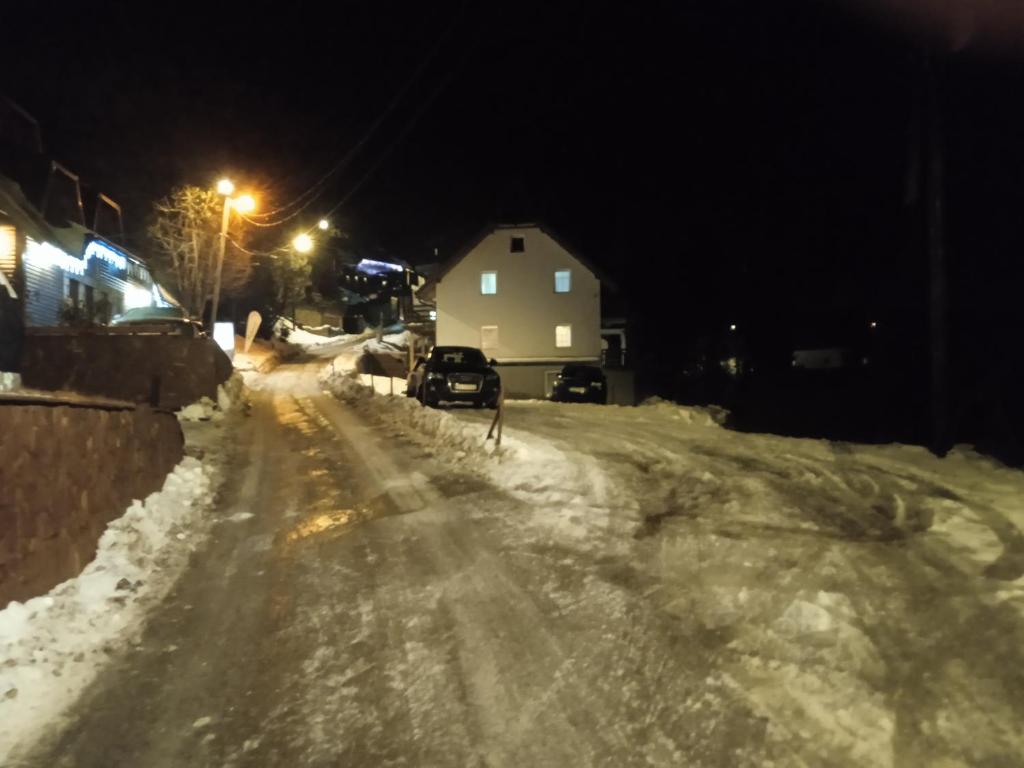 a snow covered street at night with a house at Apartments Panovic in Kopaonik