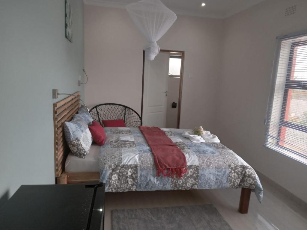 ein Schlafzimmer mit einem Bett mit einer Decke und einem Fenster in der Unterkunft Chaya accommodation B&B and self catering in Mzuzu