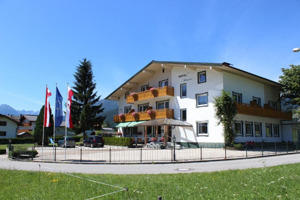 a large white building with flags in front of it at Naturparkhotel Florence in Weissenbach am Lech