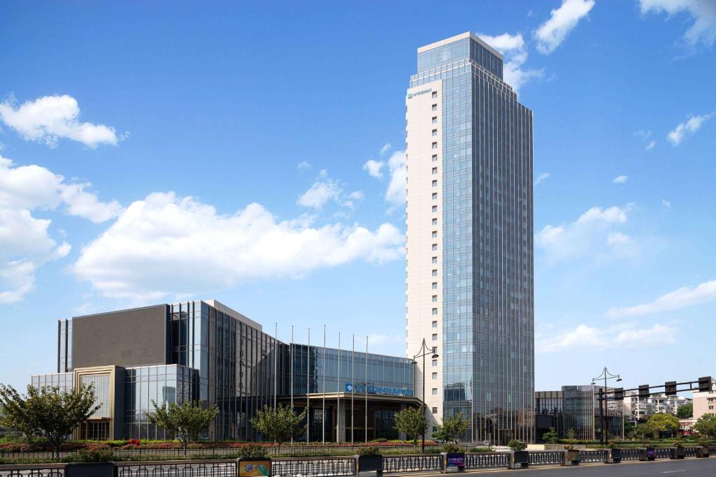 un haut gratte-ciel en verre devant une ville dans l'établissement Wyndham Hangzhou Linping, à Hangzhou