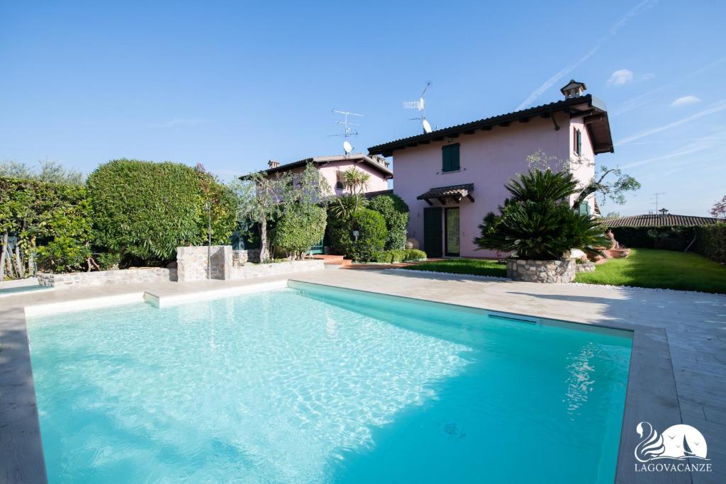 a swimming pool in front of a house at Villa Cycas in Polpenazze del Garda