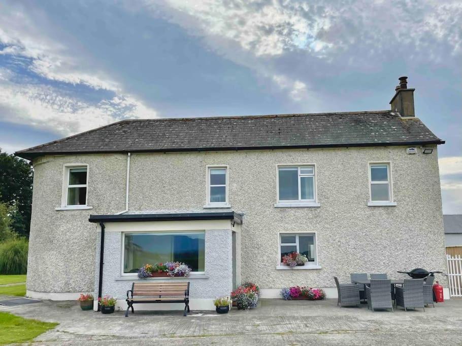 uma casa com um banco à frente em Beautiful Farmhouse an Hour’s Drive From Four Irish Cities em Clonmel