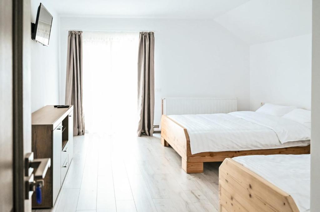 1 dormitorio con 2 camas y ventana en Pensiunea Abrudan, en Scrind-Frăsinet