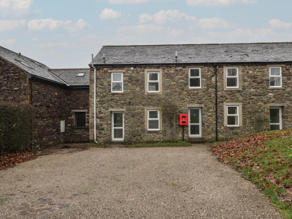 an old brick house with a red door and a driveway at 8 Little Mell Fell in Penrith