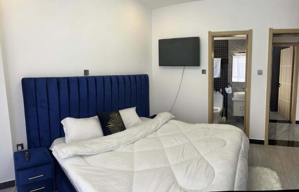 une chambre avec un grand lit et une tête de lit bleue dans l'établissement Starroot Residences, à Nairobi