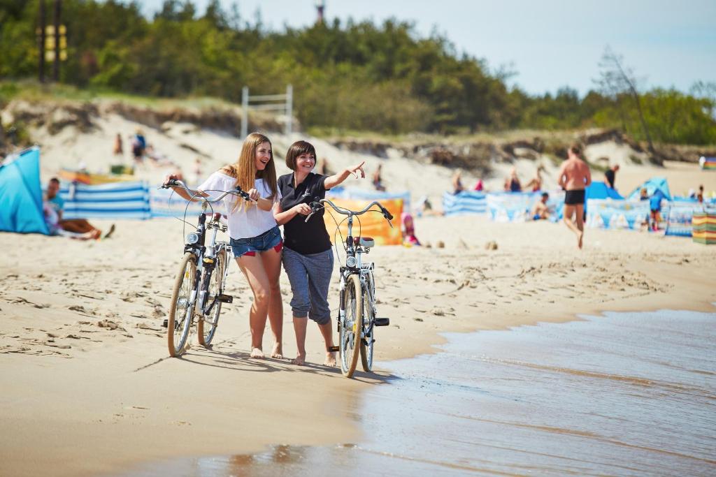 two girls walking their bikes on the beach at Kormoran Medispa in Rowy