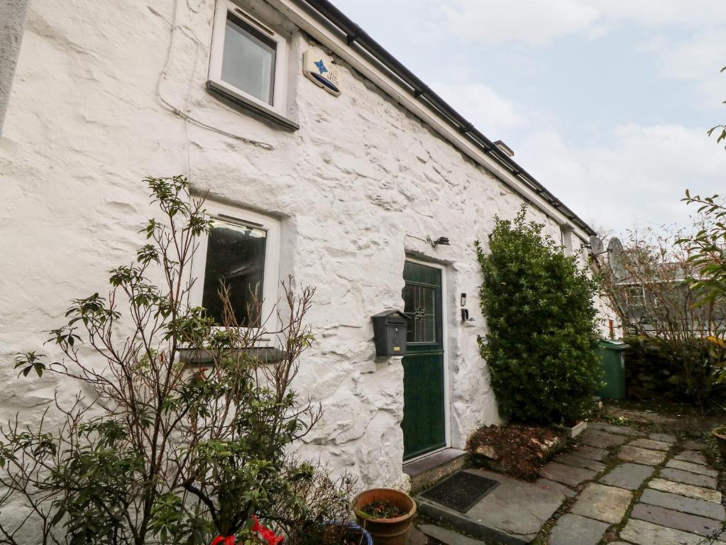 uma casa branca com uma porta verde e um quintal em Is Y Graig em Caernarfon