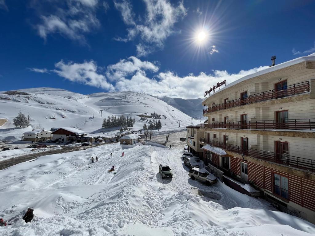 a ski resort with a snow covered mountain in the background at L'escale Du Mzaar in Fārayyā
