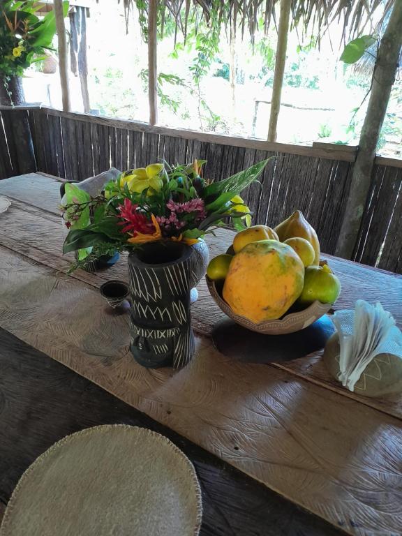 una mesa de madera con un jarrón de fruta y flores en HOSPEDAJE NAI-CHAMBIRA, en Santa Sofía